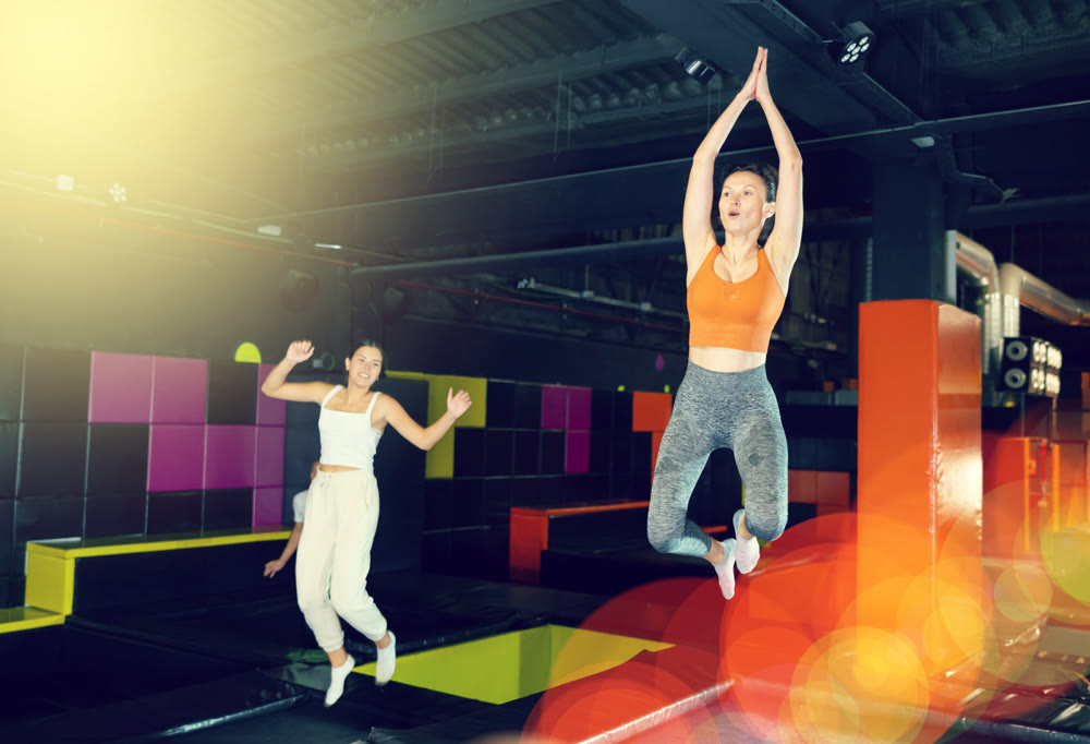 Excited woman enjoying jumping at well-equipped indoor trampoline arena