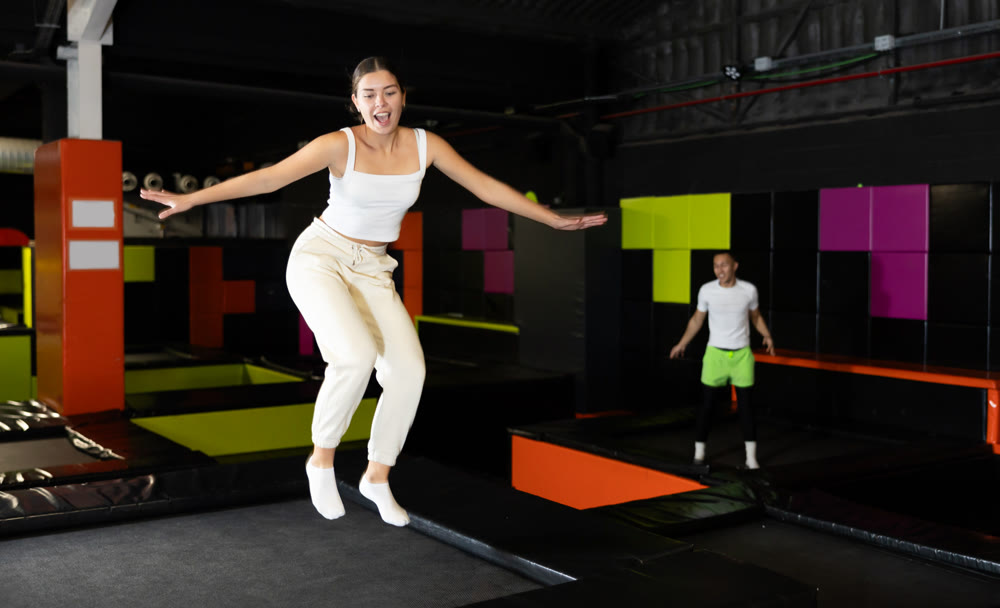 Girl acrobatic athlete jumping and exercising on trampoline indoors, modern hobby and fitness concept