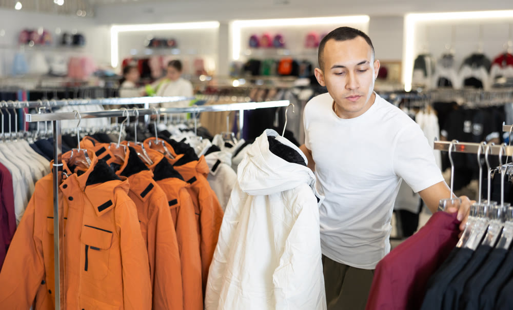 Young man choosing jacket in store