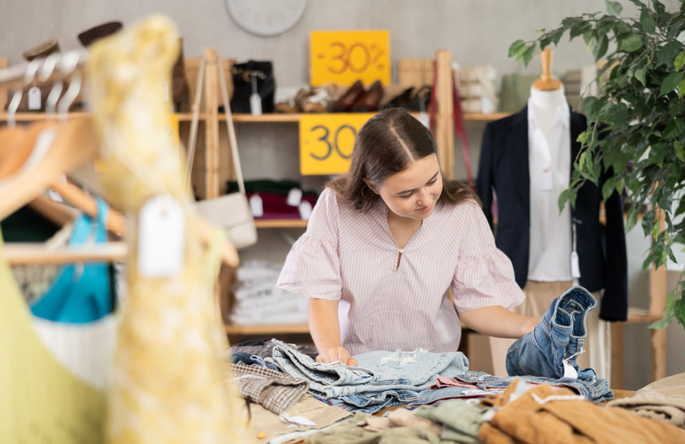 Positive teenage girl choosing pantaloon in clothing store