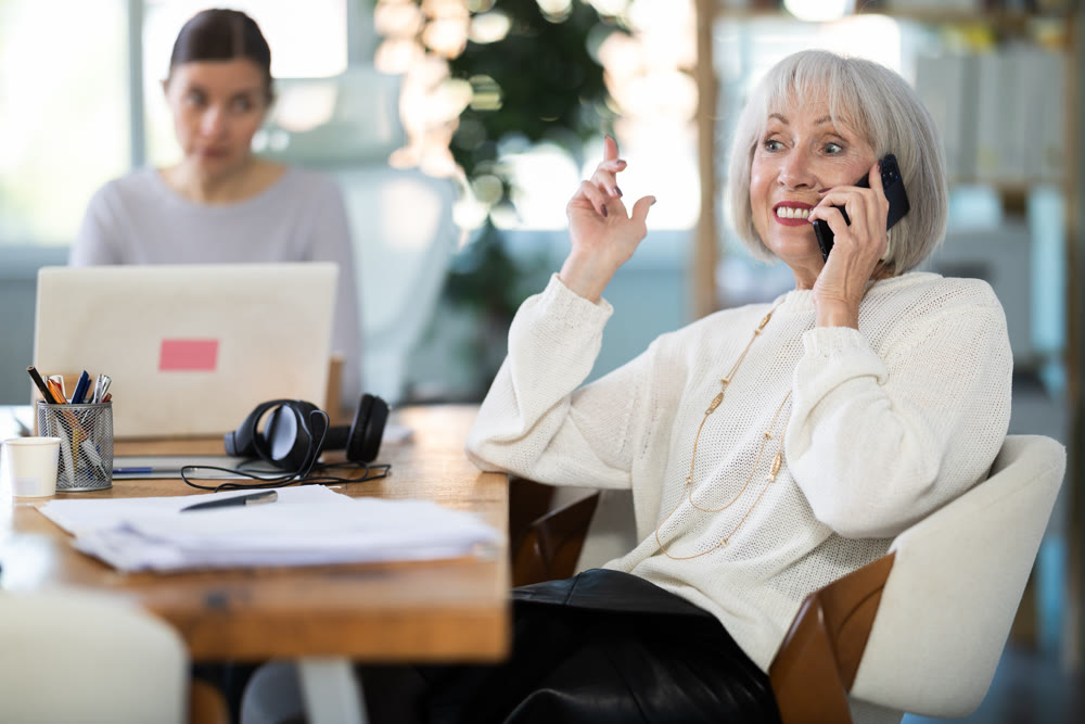 Adult woman judging female colleague talking on mobile phone