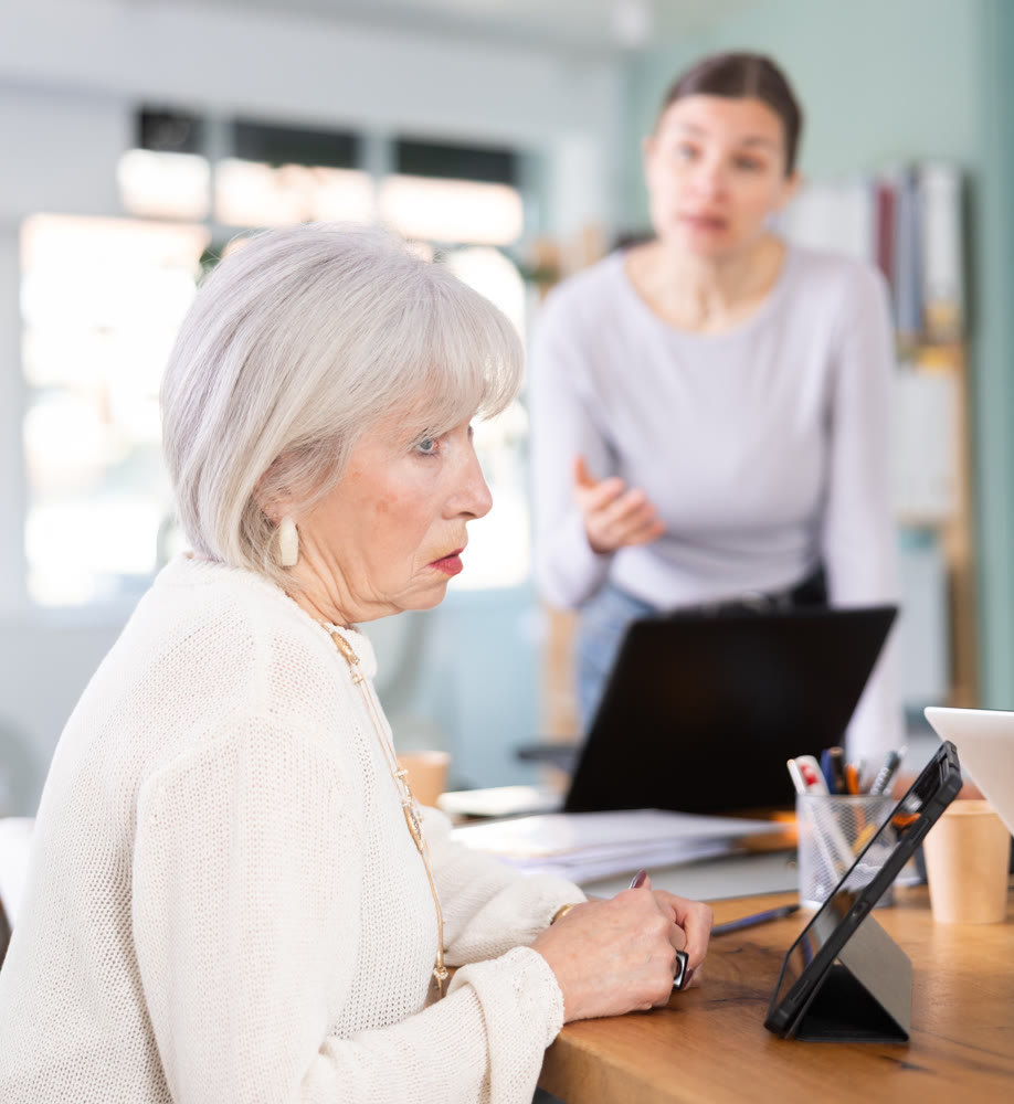 Adult woman scolding female colleague working on tablet