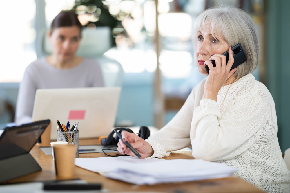 Adult woman judging female colleague talking on mobile phone