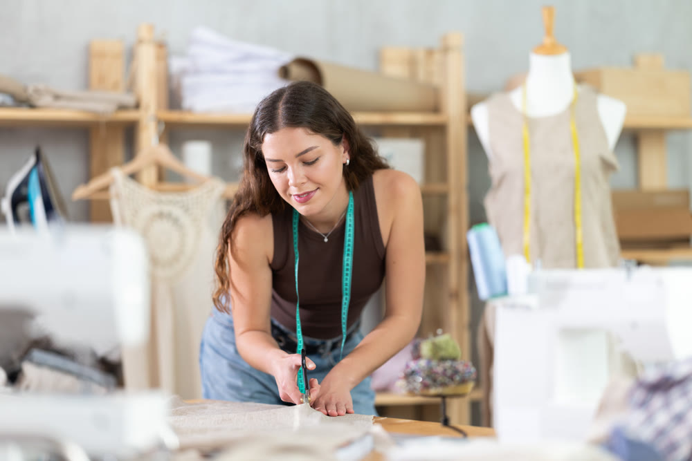 Woman tailor cutting fabric on table