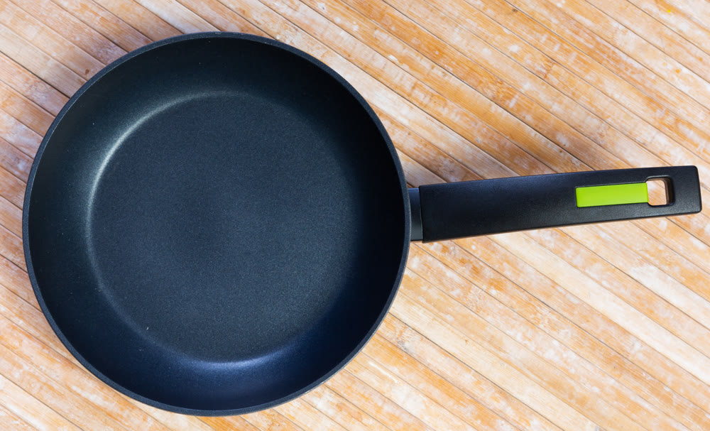 New frying pan with non-burning coating on wooden background