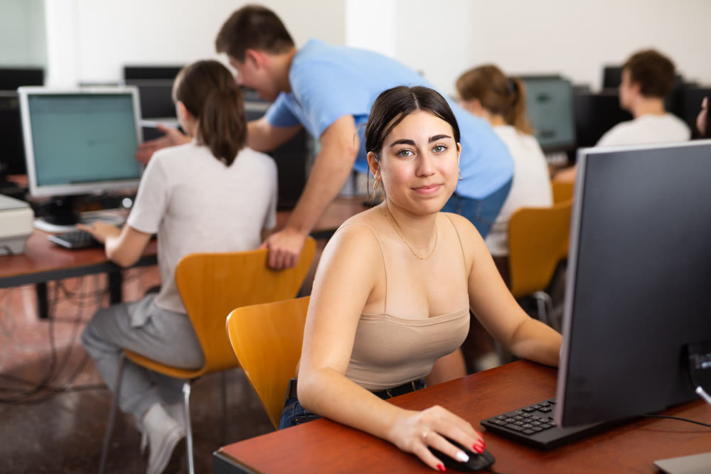 Portrait of female schoolgirl at computers in university class