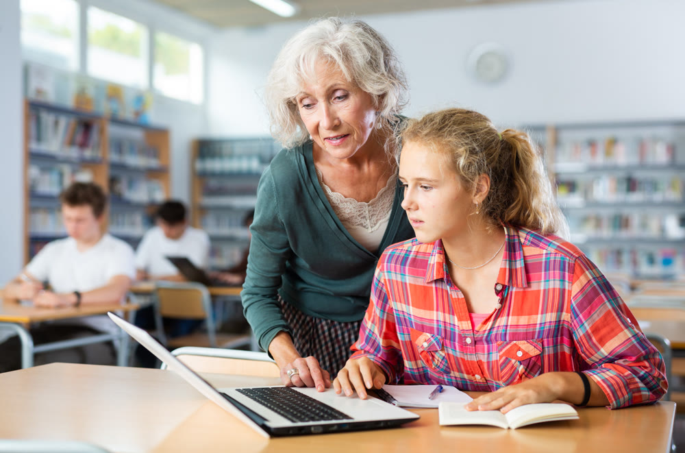 Female teacher cheks the assignment from a European schoolgirl