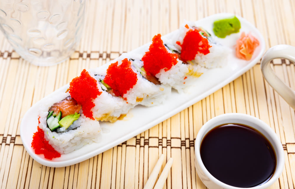 Sushi roll uramaki - tobiko roll with salmon, avocado, pepino, tobiko