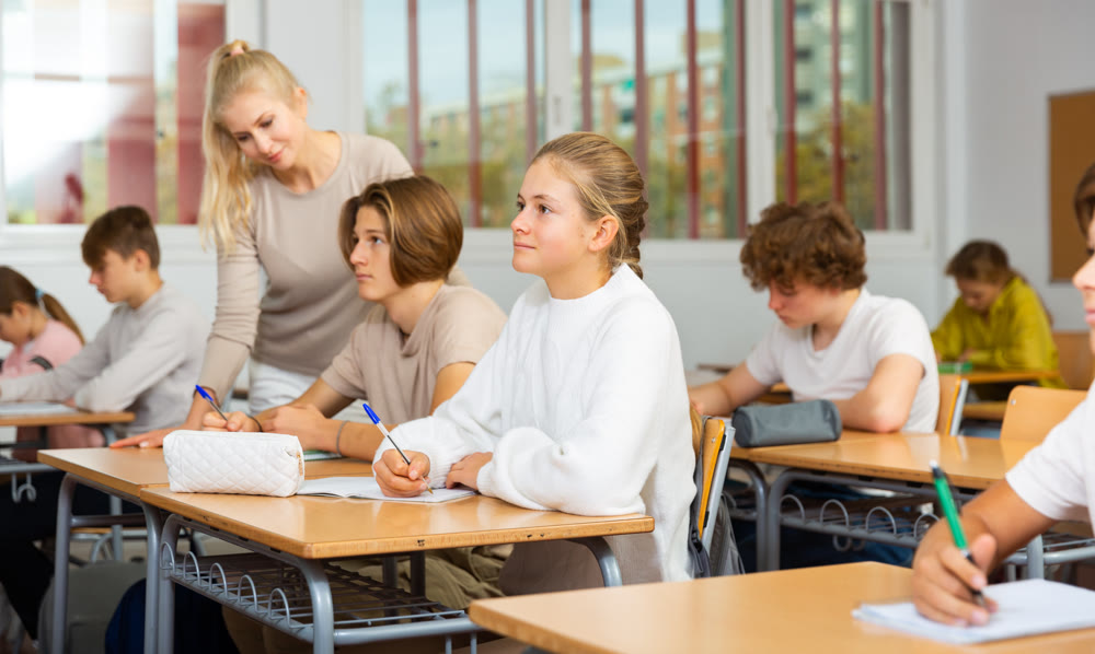 Teenagers sitting at desks in classroom during lesson