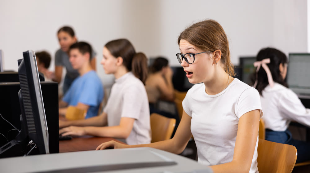 Amazed teenager girl using PC during computer science lesson