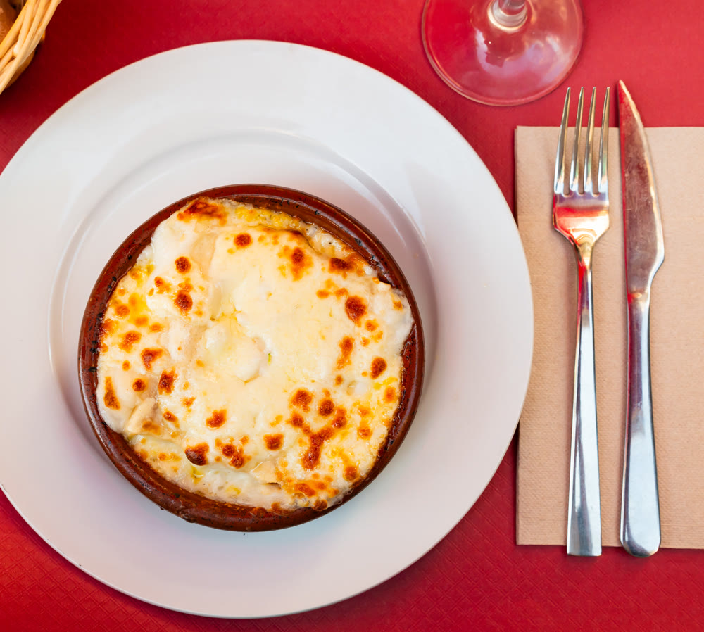 Portion of cannelloni with minced beef, covered with sauce, served on table in restaurant