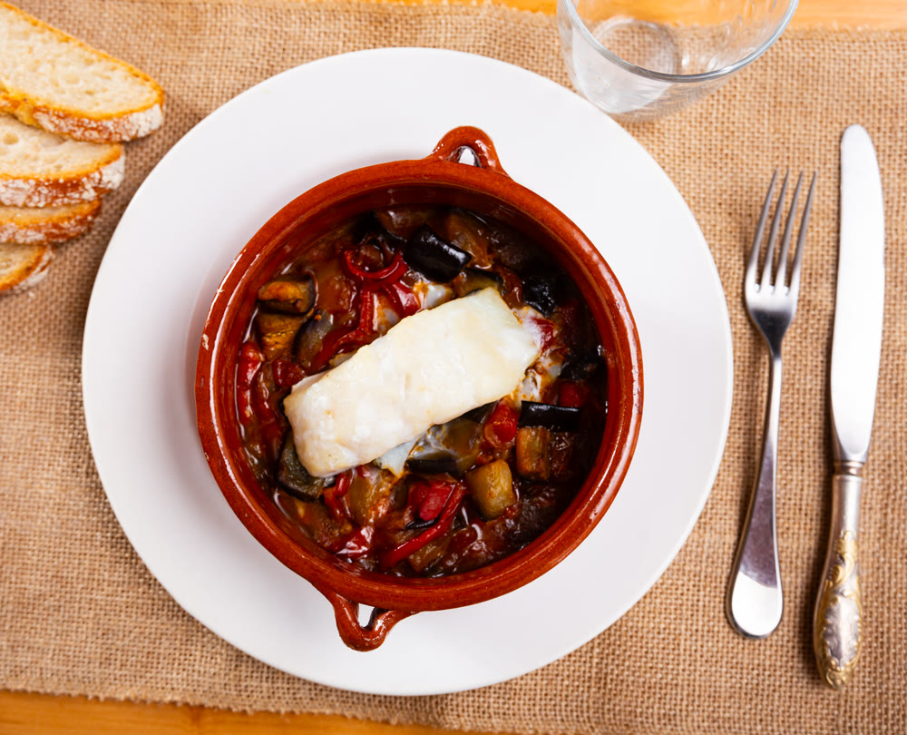 Hearty lunch, cooked xanfaina cod with seasonal vegetables in baking dish.