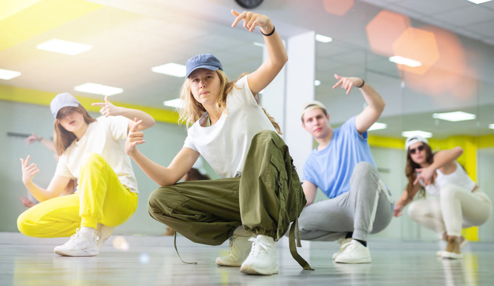 Teenage girl sitting in breakdance pose in dance hall