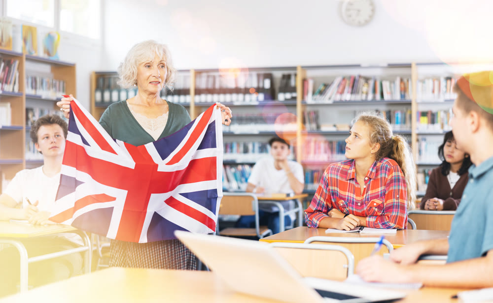 Mature female teacher shows scholchildren the national flag of Great Britain