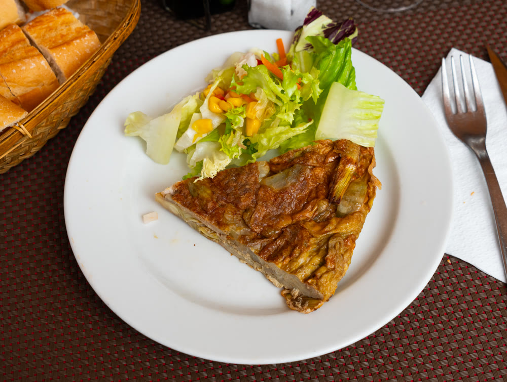 Traditional Spanish artichoke tortilla with fresh salad