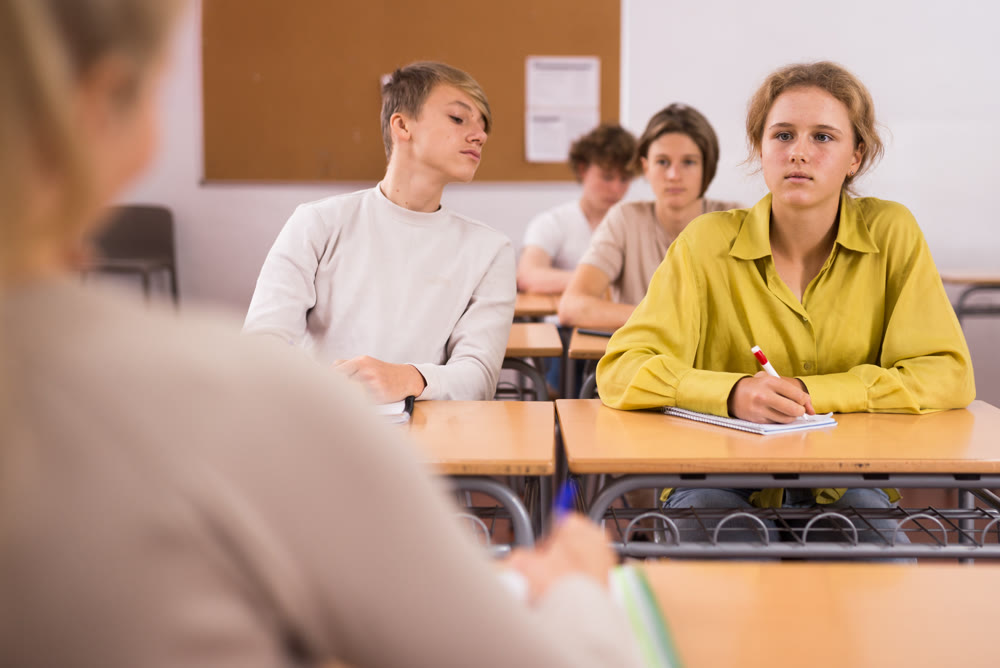 Group of students working at class, listening explanations of teacher in classroom