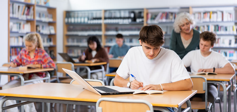 Teenager student sitting at desk in classroom at lesson in high school