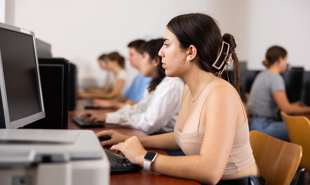 Side view on diligent college girl studying using pc in computer class