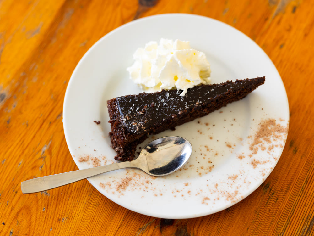 Delicious slice of brownie cake on plate with whipped cream
