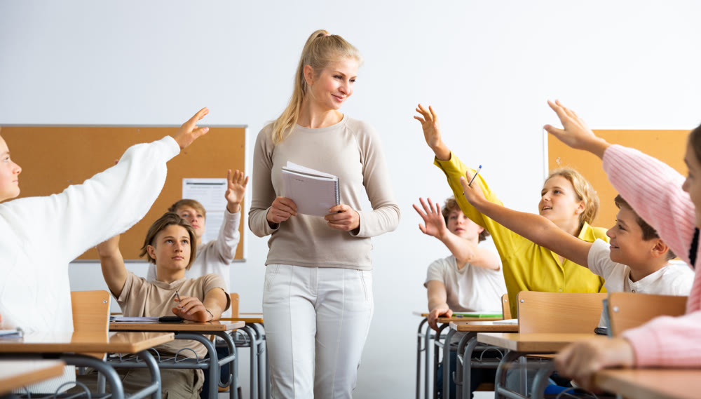 Pupils raising hands during lesson in school