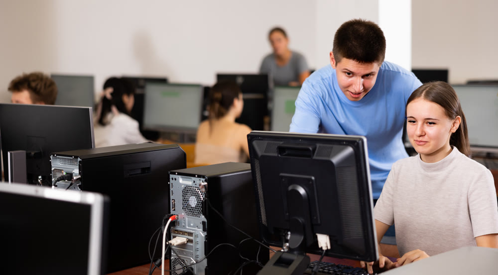 Cheerful teenager boy and girl studying in computer class