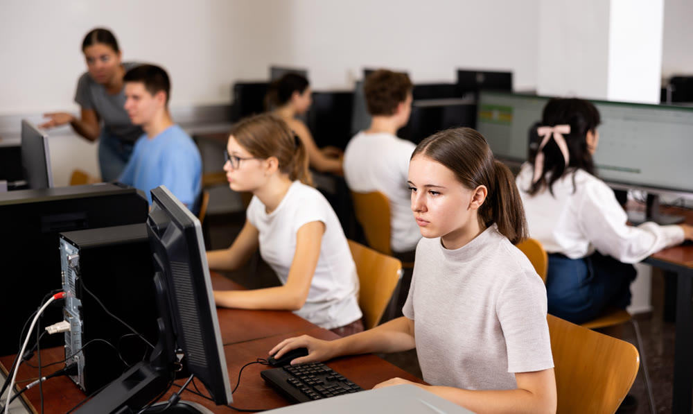Portrait of female schoolgirl at computers in university class