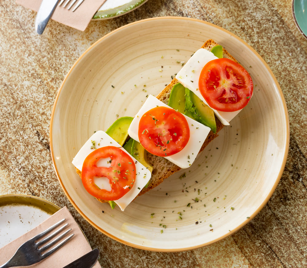 Open-faced sandwich with tomato, avocado, and cheese