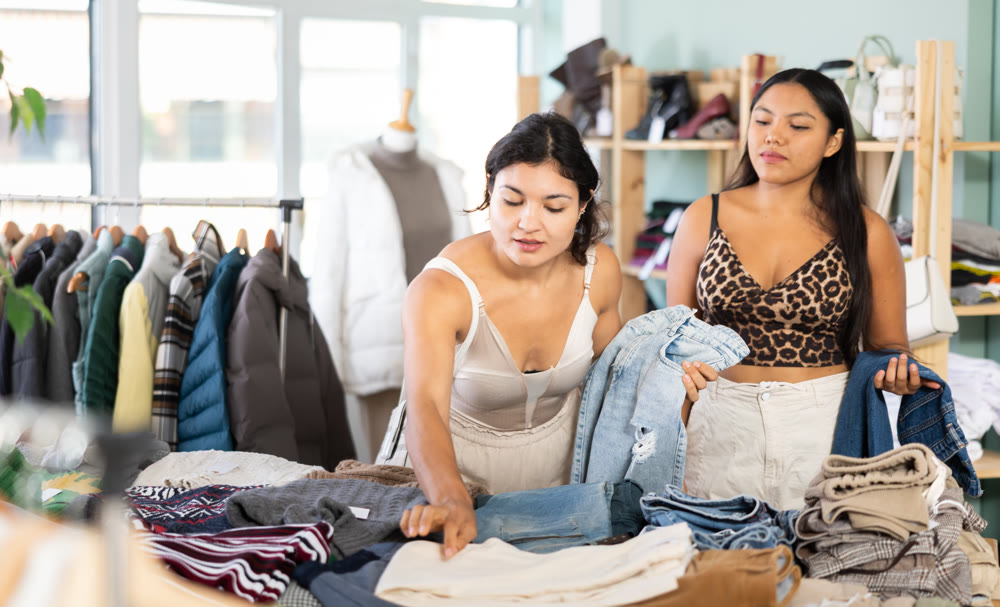Two girlfriends chooses fashionable jeans in fashionable clothing store