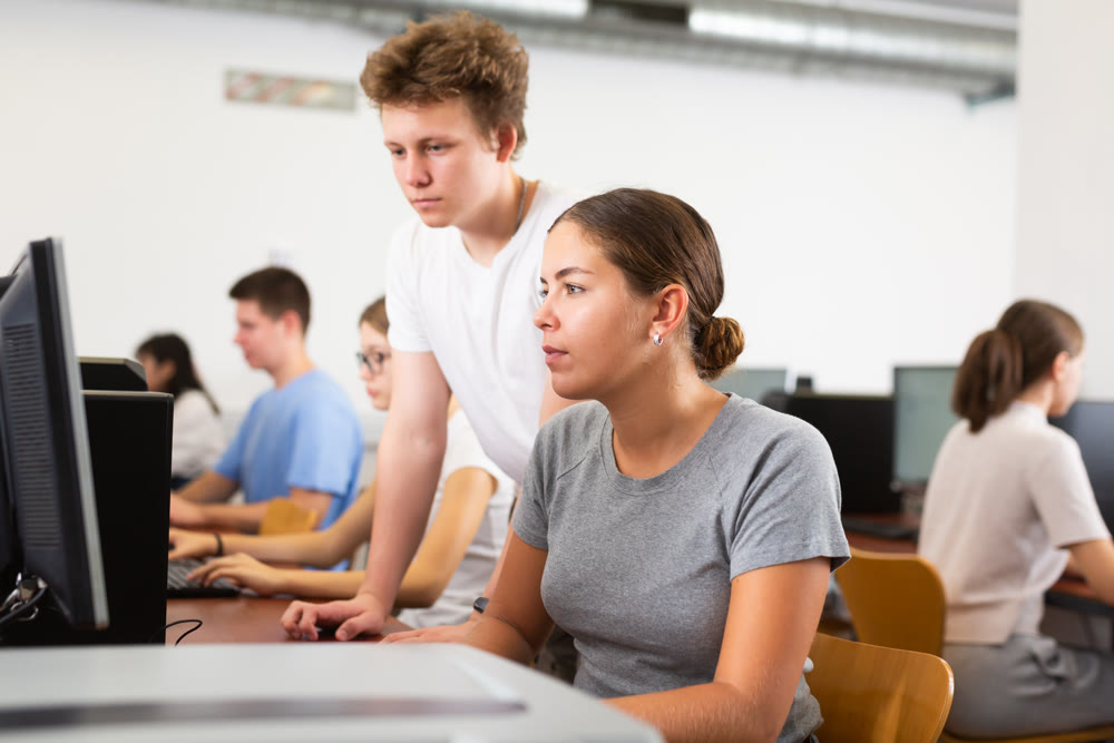Teacher and teenage student studying in computer class