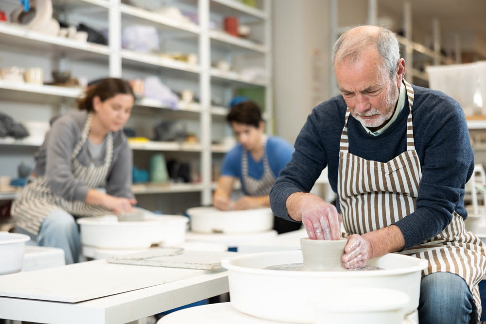 Eldery man shaping pottery on wheel in ceramics studio