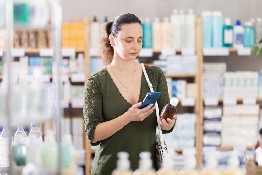 Middle-aged woman customer choosing syrup in drugstore
