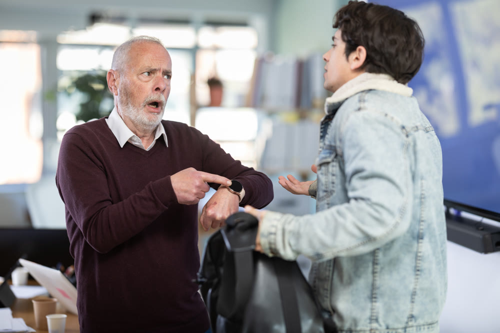 Mature boss scolds an male employee for being late for work