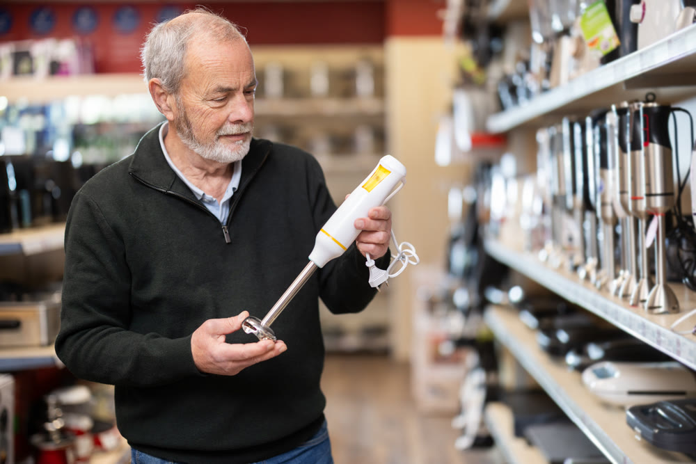 Elderly man choosing a blender in a store