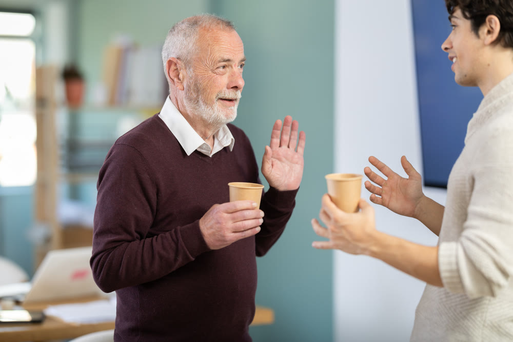 Two office workers drink coffee and chat during work break
