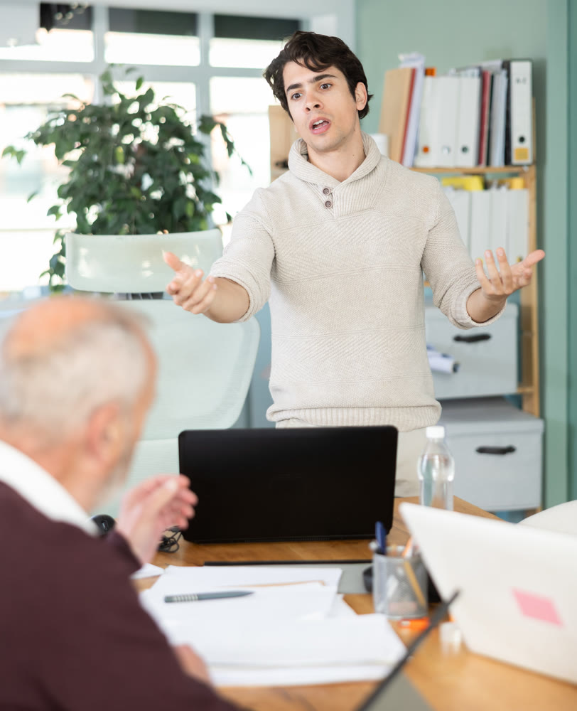 Guy head of department shouts at senior man subordinate who is working with documents
