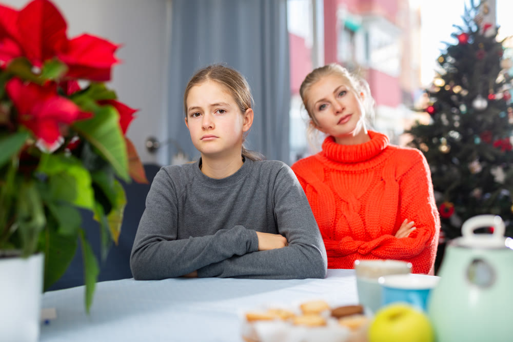 Schoolgirl sitting at the table after quarrel with mother
