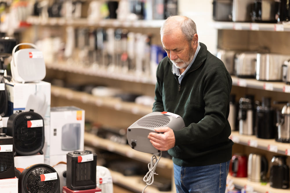 Senior man customer inspect product range and selects fan heater