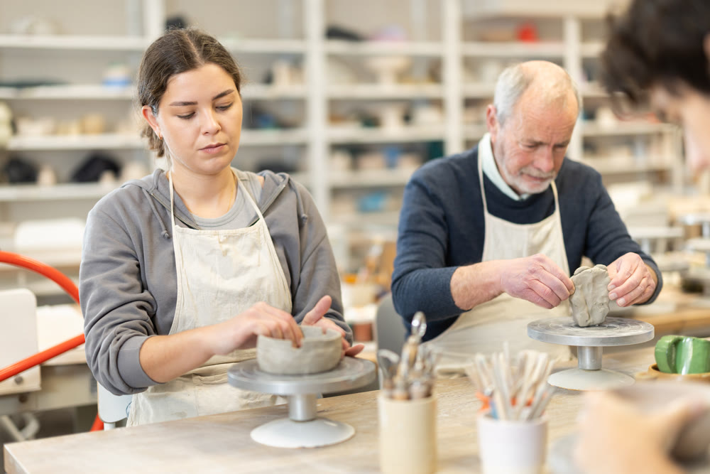 During working day, three pottery workshop workers sculpt from clay, form final product