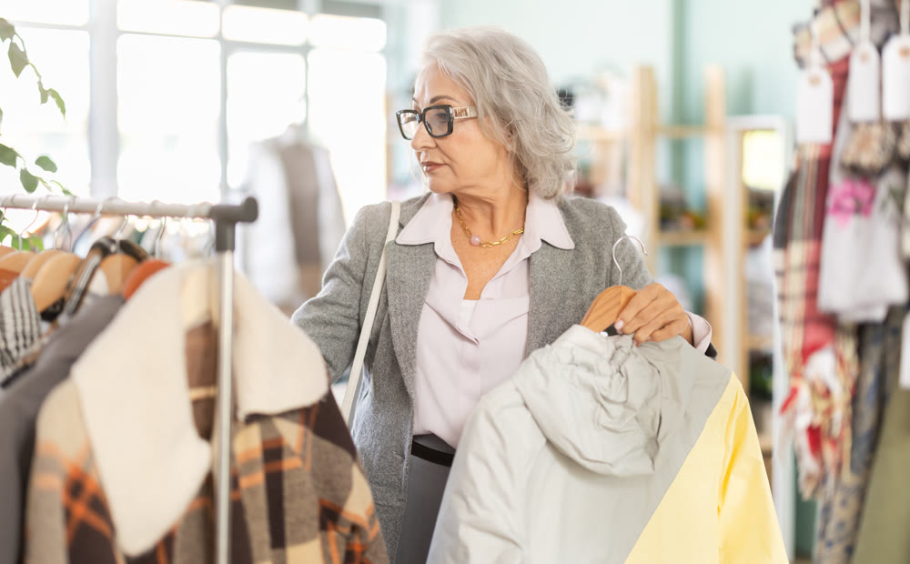 Family clothing store, senior woman customer chooses jacket or coat