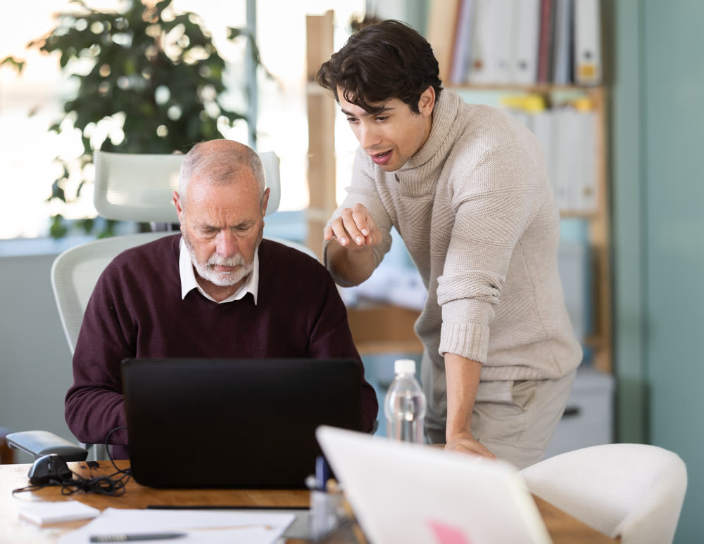 Guy help an older manager learn to use laptop