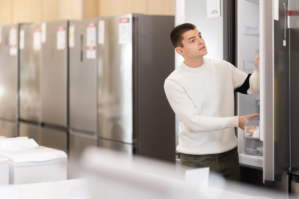Guy choosing a refrigerator in an equipment store
