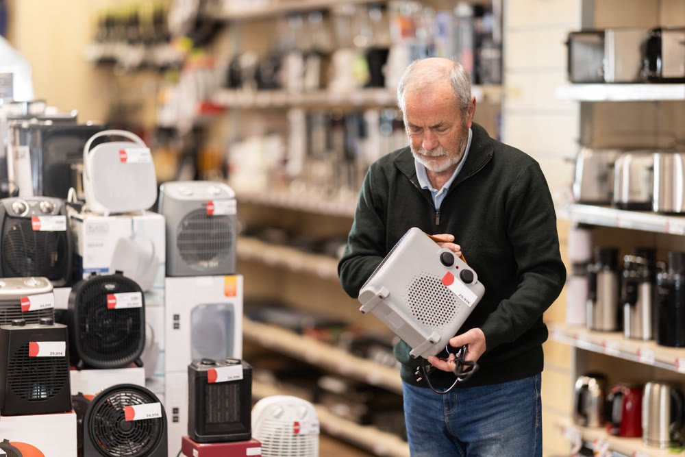 Eldery man chooses portable heater in appliance store