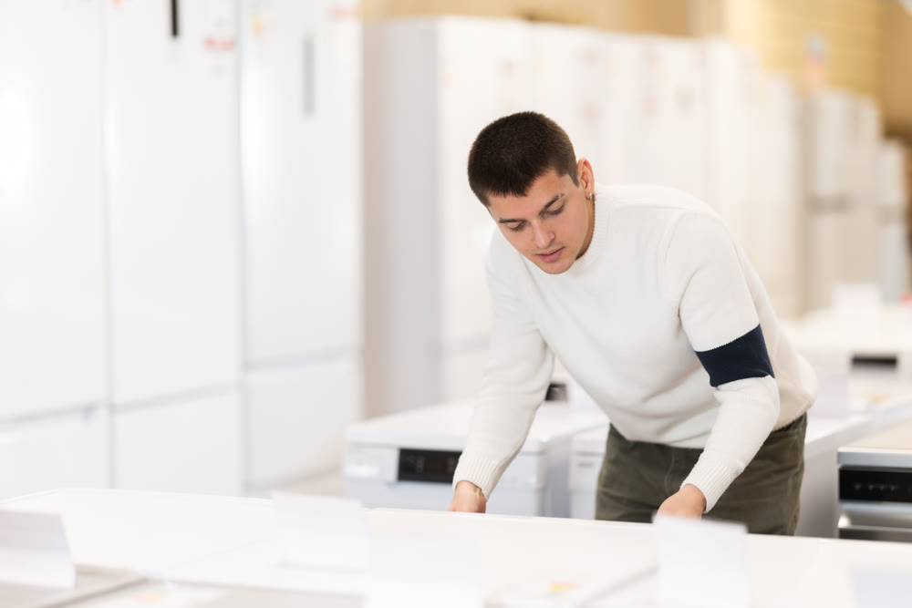 Guy choose modern washing machine or dishwasher at supermarket