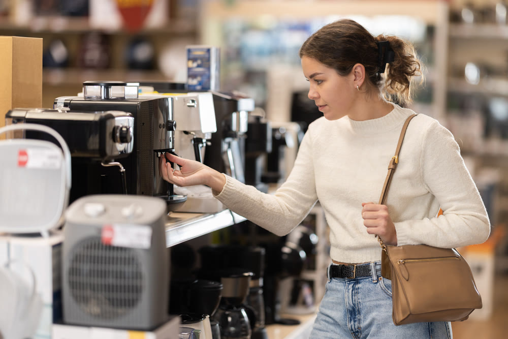 Young woman chooses coffee machine in appliance store