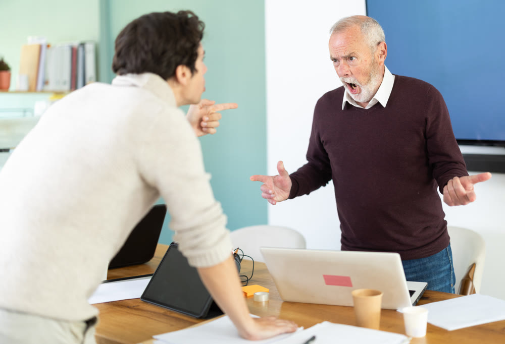 Elderly and young men arguing loudly in office