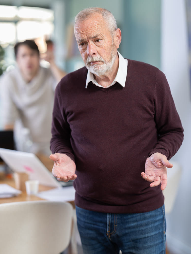 Young man scolds elderly man in office