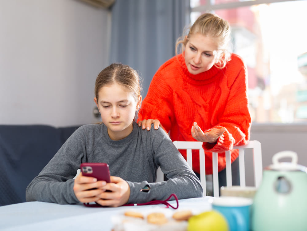 Daughter plays on smartphone while mother tries to talk to her