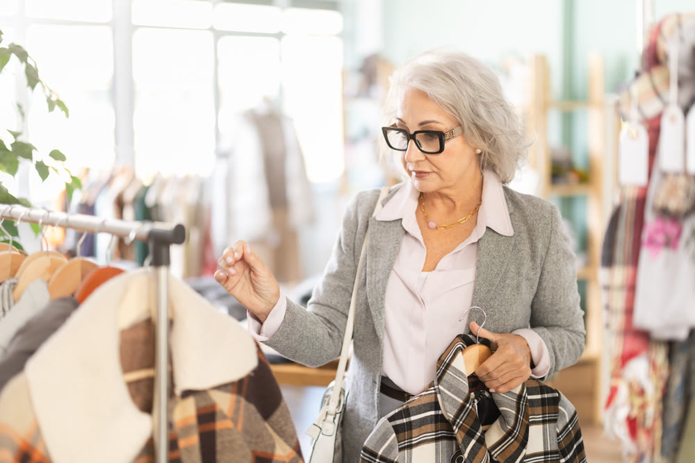 Family clothing store, senior woman customer chooses jacket or coat