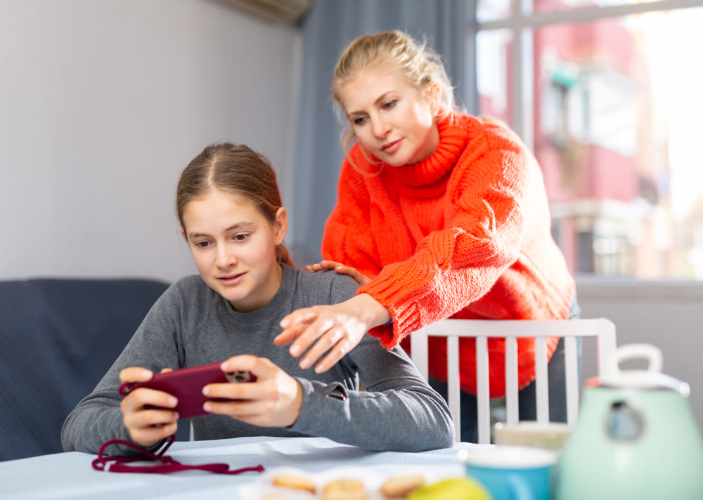 Daughter plays on smartphone while mother tries to talk to her