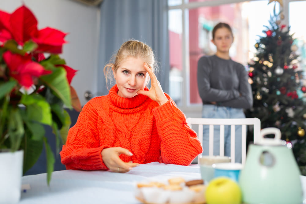 Mom sitting at table after quarreling with daughter during christmas time